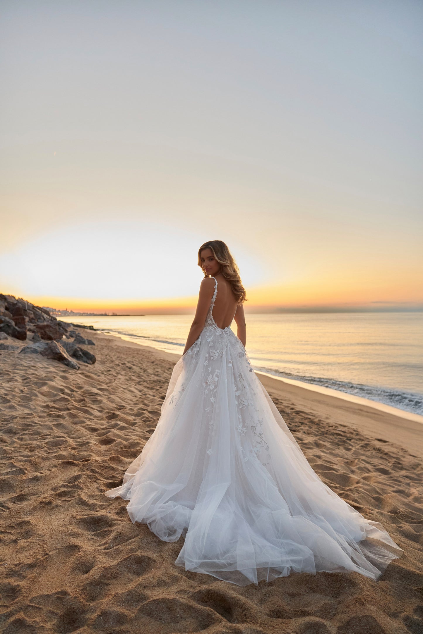 Sleeveless lace A-line bridal gown with spaghetti straps, deep-V neckline, backless zip closure, lace tulle skirt, and chapel train.