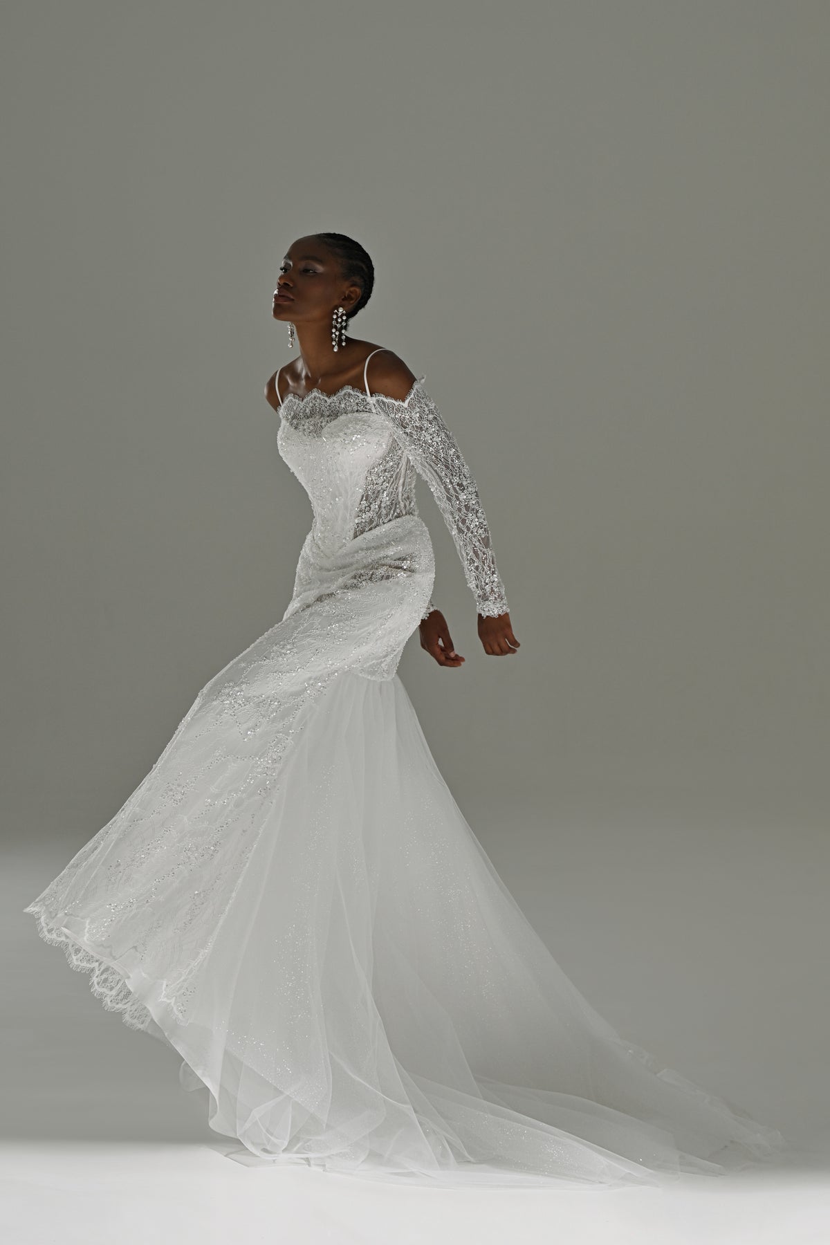 Off-shoulder lace mermaid wedding dress – three-quarter view with the tulle skirt flowing