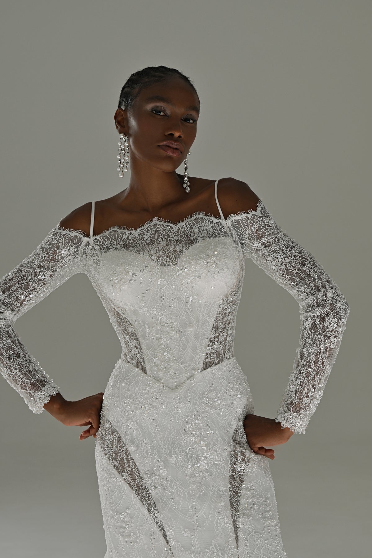 Off-shoulder lace mermaid wedding dress – front view of the lace bodice with hands on hips