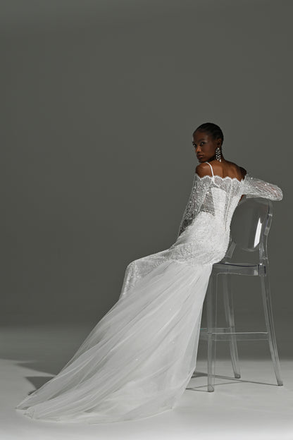 Off-shoulder lace mermaid wedding dress – model seated on a stool with the tulle train spread out