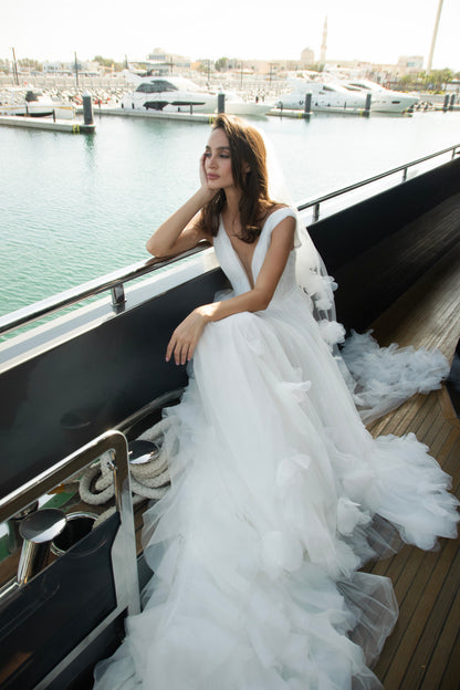 Ethereal tulle ball gown with deep V-neckline and layered airy skirt.