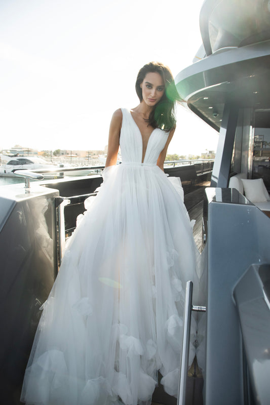 Ethereal tulle ball gown with deep V-neckline and layered airy skirt.