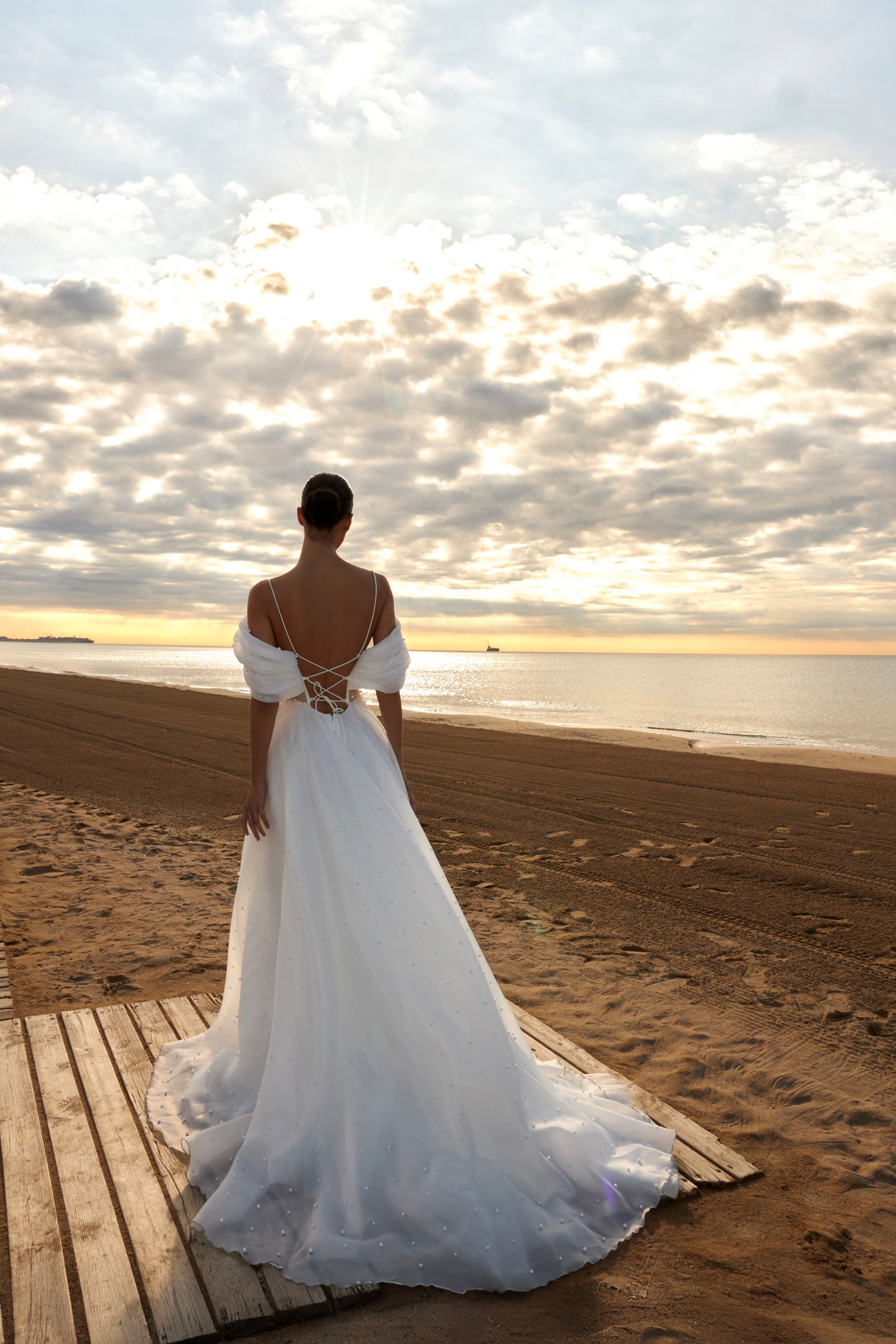 Organza A-line bridal gown with off-shoulder crossed draped neckline, spaghetti straps, pearl details, slit skirt, open back lace-up closure, and court train.