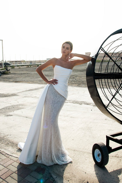 Strapless straight silhouette wedding dress with asymmetric Mikado bodice, lace skirt, zip closure, and flowing train for modern bridal style