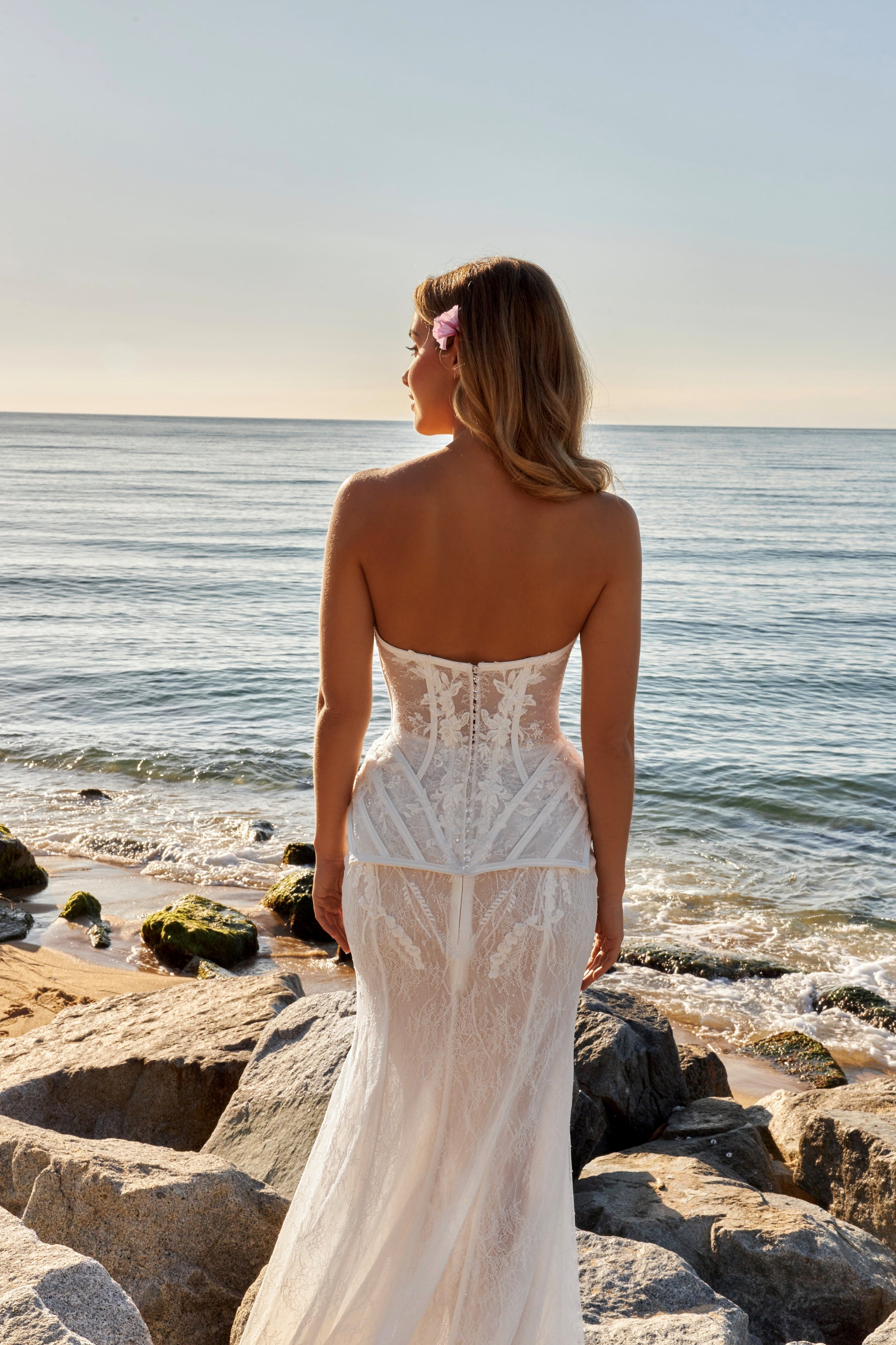 Bride in strapless lace corset wedding dress with tulle A-line slit skirt and optional fishtail train overlay.