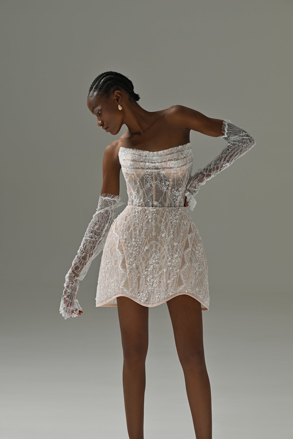 Strapless lace mini wedding dress with flared skirt – front view, model looking down with lace sleeves
