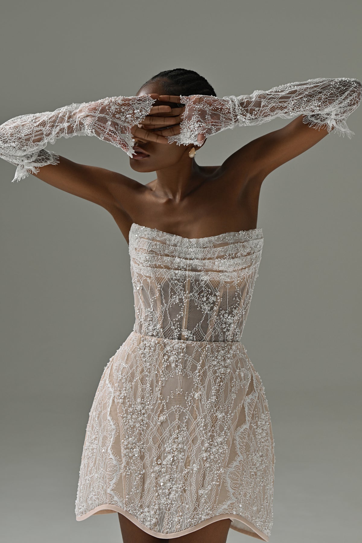 Strapless lace mini wedding dress – bodice and skirt detail with lace sleeves raised over the face