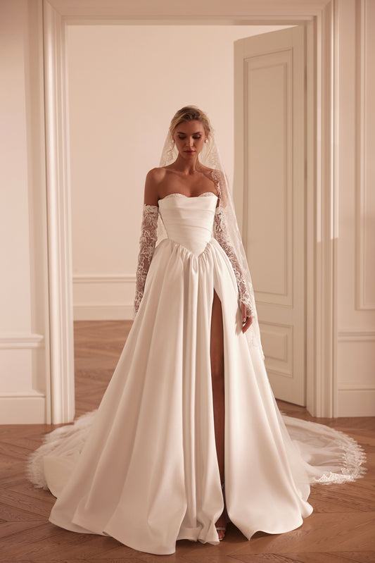 Bride wearing an off-shoulder A-line Mikado wedding dress with corset back, thigh-high slit, and chapel train.