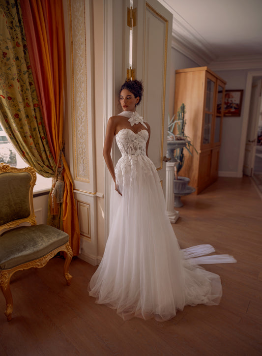 Bride wearing a floral appliqué A-line wedding dress with sweetheart corset and flowing tulle skirt.