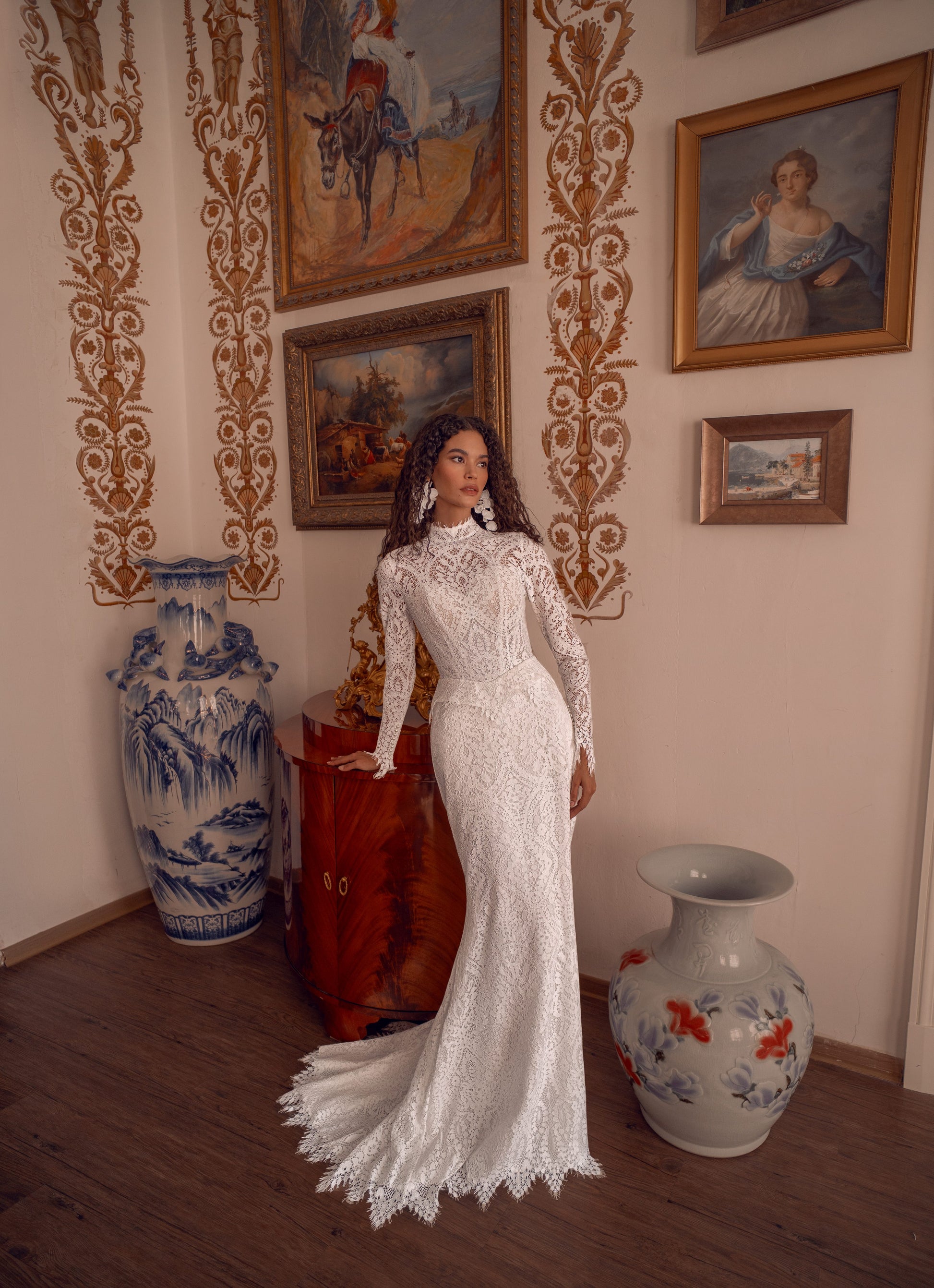 Long-sleeve high-neck lace mermaid wedding gown with open back and scalloped train.