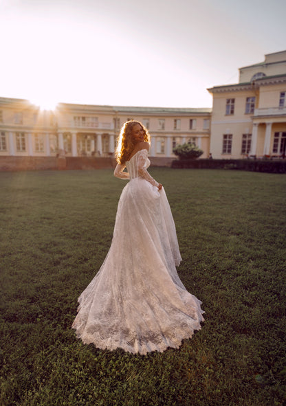 Romantic off-shoulder lace A-line wedding gown with long sleeves and corset bodice.