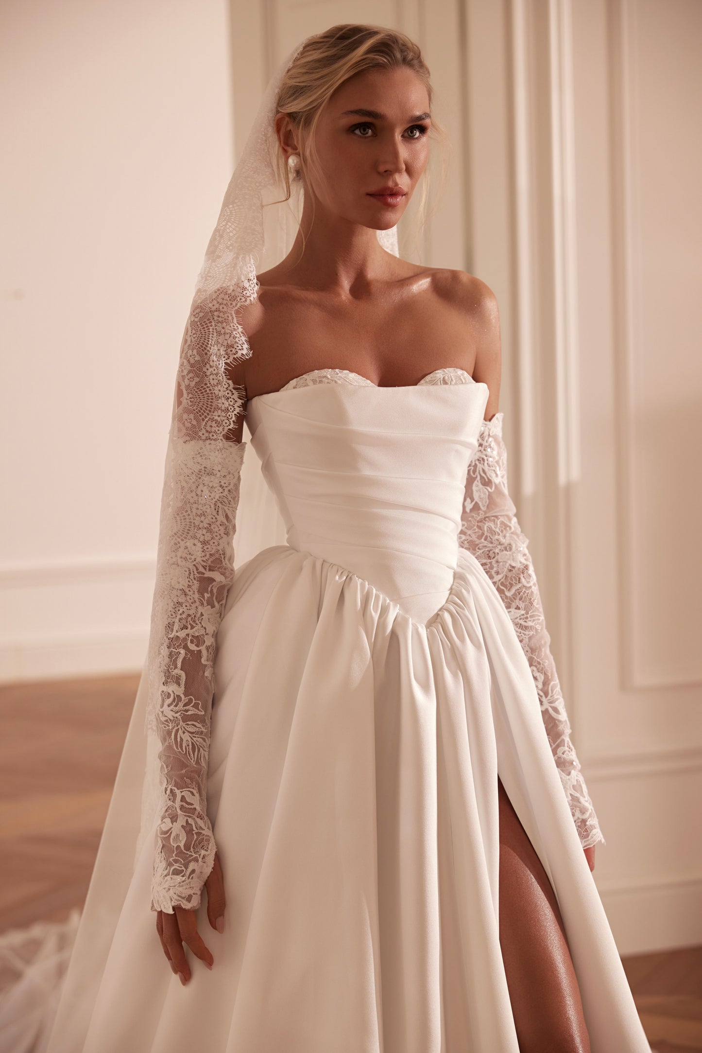 Bride wearing an off-shoulder A-line Mikado wedding dress with corset back, thigh-high slit, and chapel train.
