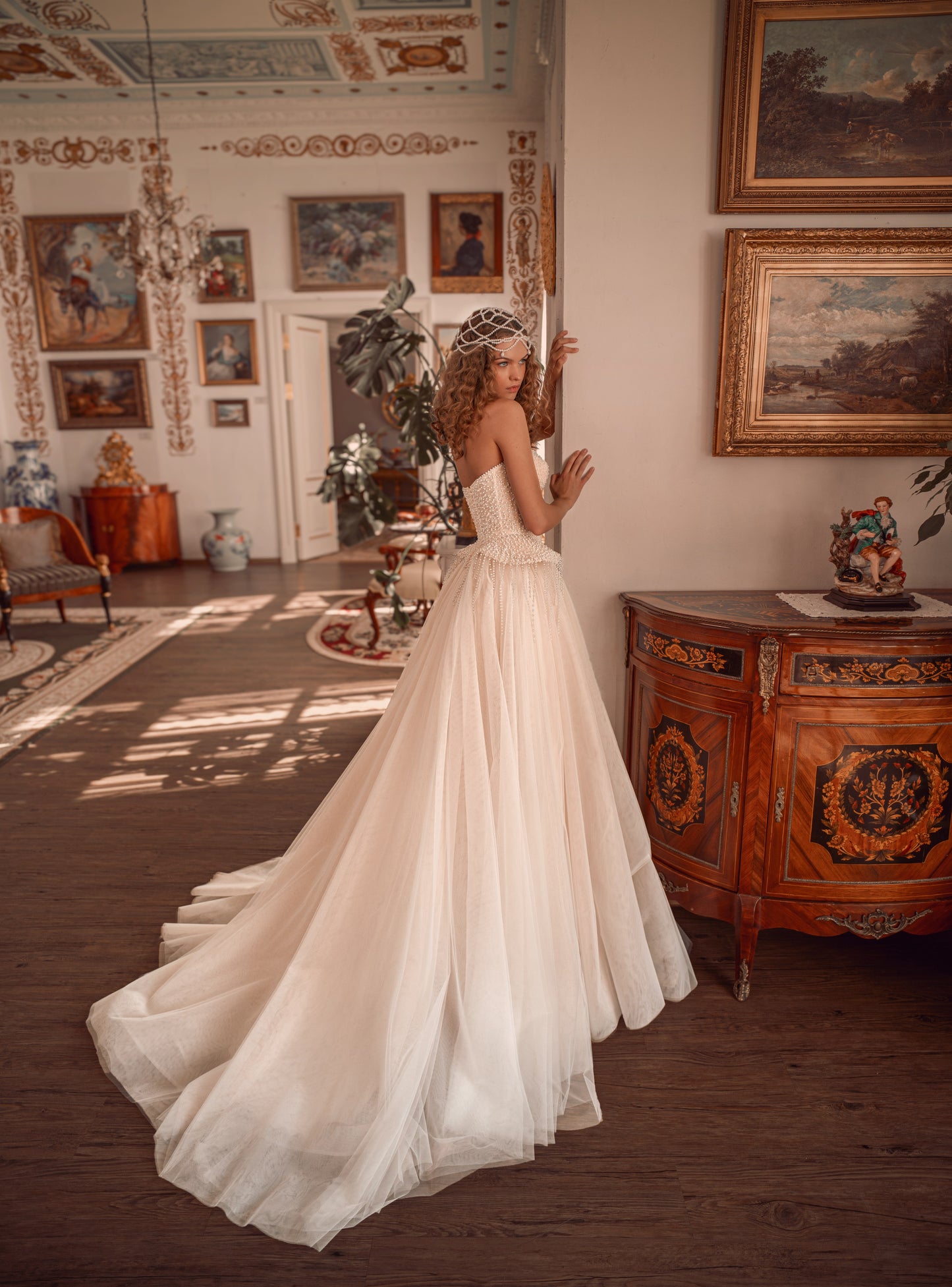 Bride wearing a pearl-embroidered corset ball gown with soft tulle skirt and flowing train.