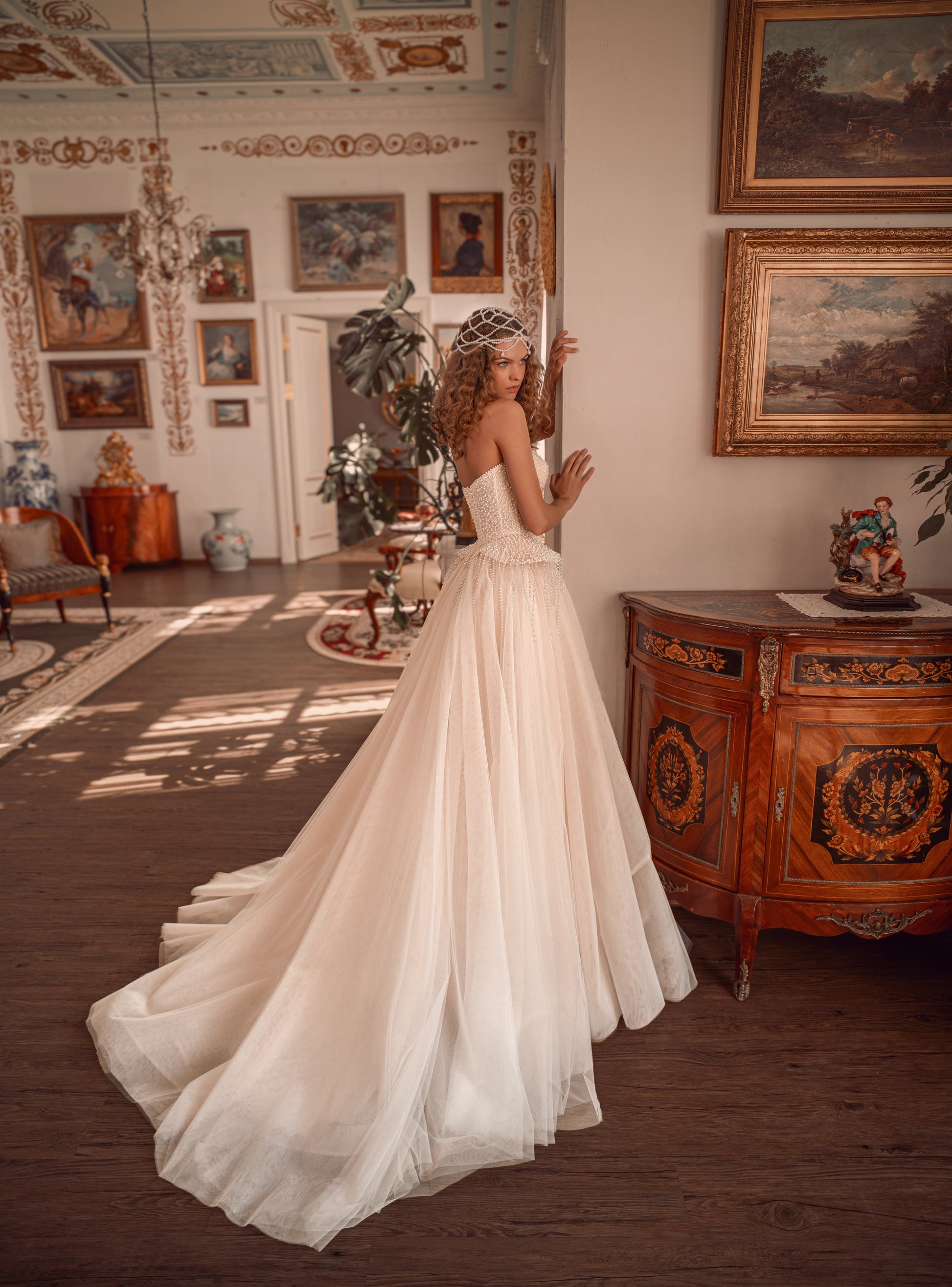 Bride wearing a pearl-embroidered corset ball gown with soft tulle skirt and flowing train.