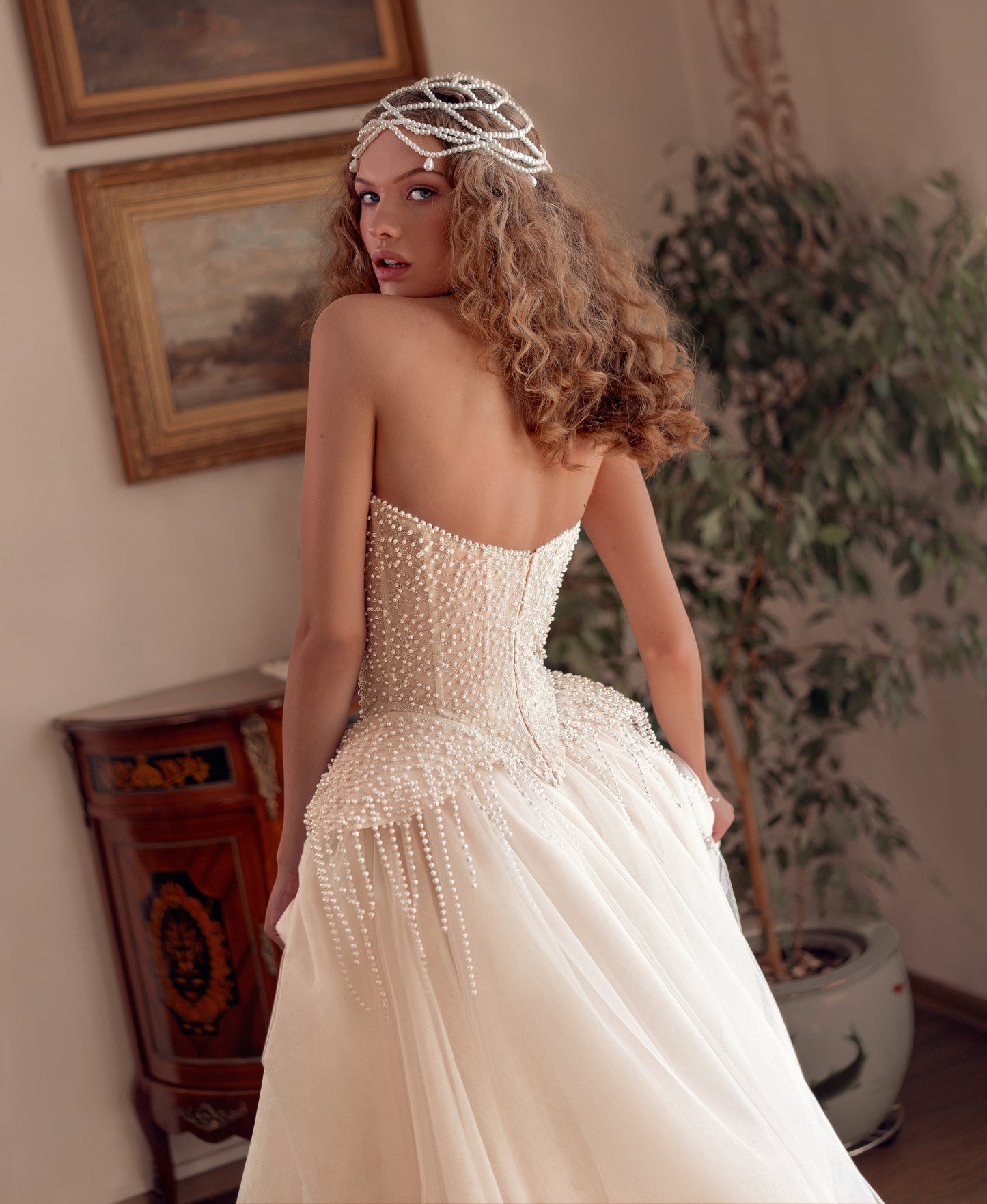Bride wearing a pearl-embroidered corset ball gown with soft tulle skirt and flowing train.