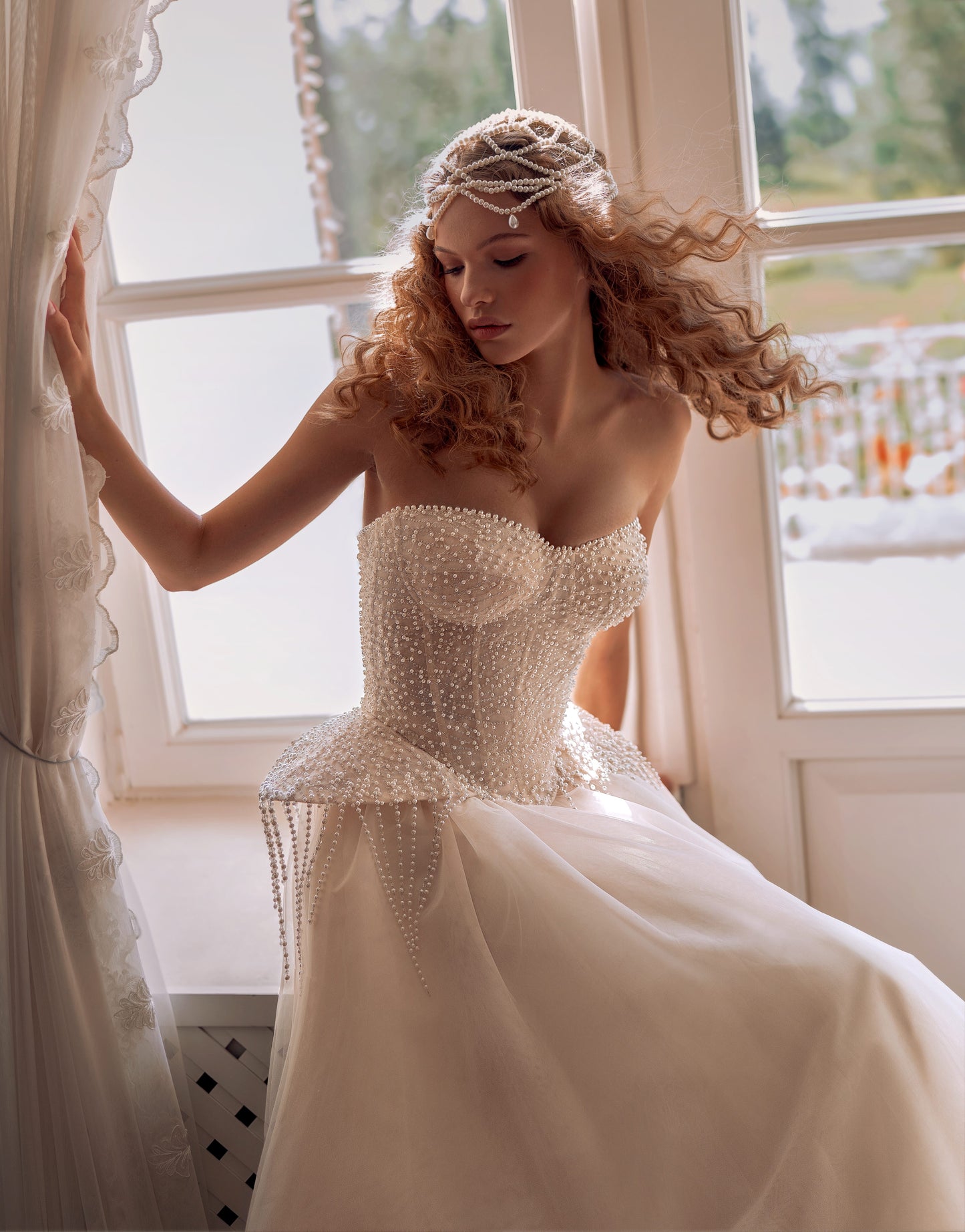 Bride wearing a pearl-embroidered corset ball gown with soft tulle skirt and flowing train.