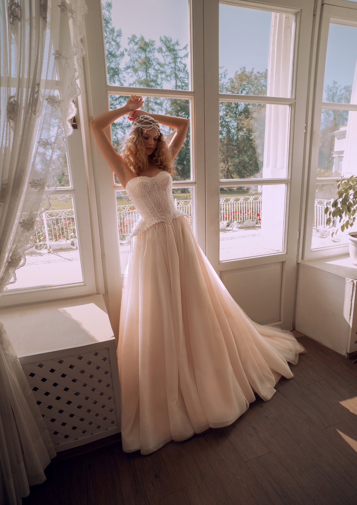 Bride wearing a pearl-embroidered corset ball gown with soft tulle skirt and flowing train.