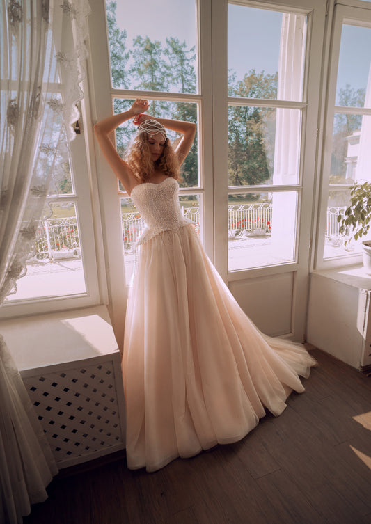 Bride wearing a pearl-embroidered corset ball gown with soft tulle skirt and flowing train.