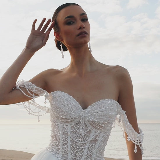 Sleeveless A-line wedding dress with pearl bodice, sweetheart neckline, glitter tulle skirt, off-the-shoulder pearl straps, and chapel train.
