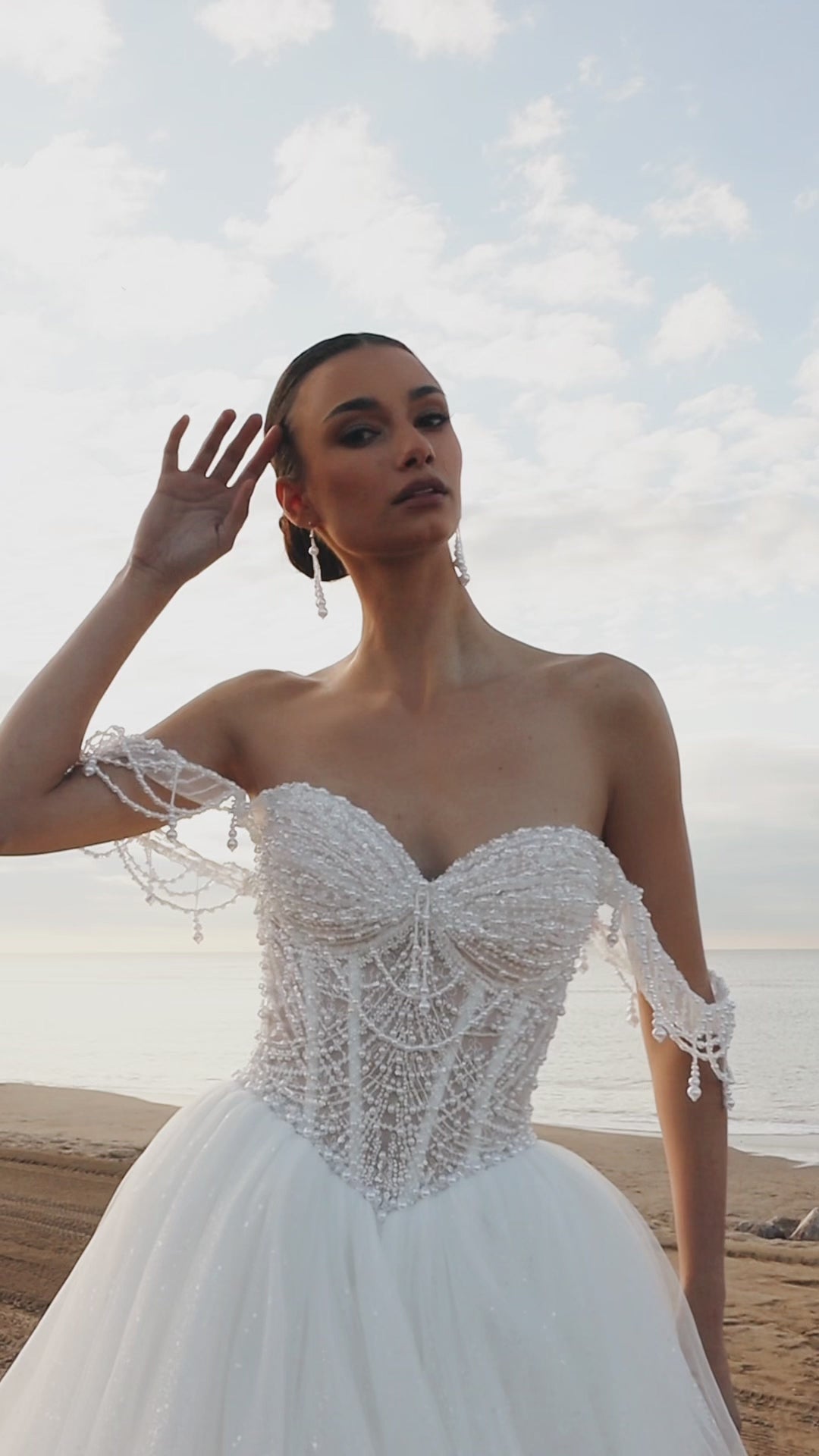 Sleeveless A-line wedding dress with pearl bodice, sweetheart neckline, glitter tulle skirt, off-the-shoulder pearl straps, and chapel train.