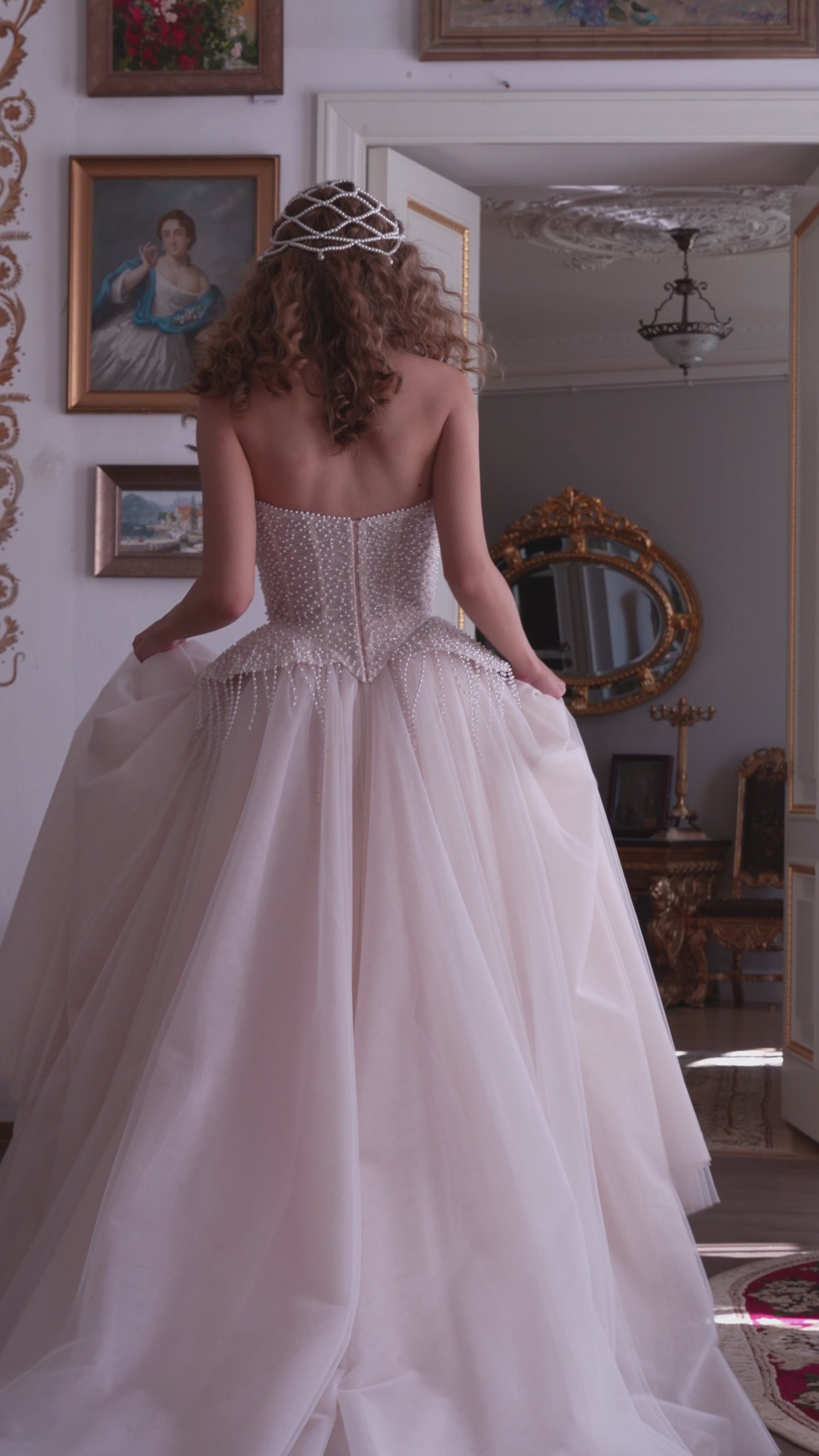 Bride wearing a pearl-embroidered corset ball gown with soft tulle skirt and flowing train.