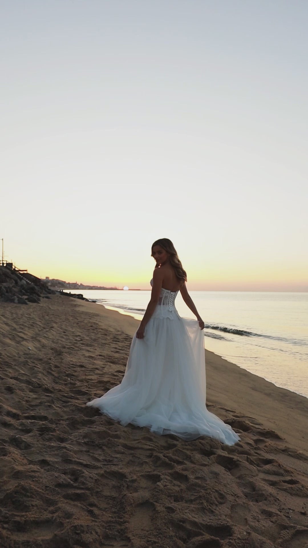 Bride in strapless lace corset wedding dress with fringe detail, lace-up back, soft tulle A-line skirt with slit, and court train.