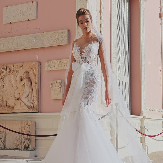 Modern mermaid wedding dress with knee-high cut, detachable waist bow, lace appliques, bead and pearl embroidery, 50 cm train, and matching veil. Made of lace and tulle for a timeless bridal look.