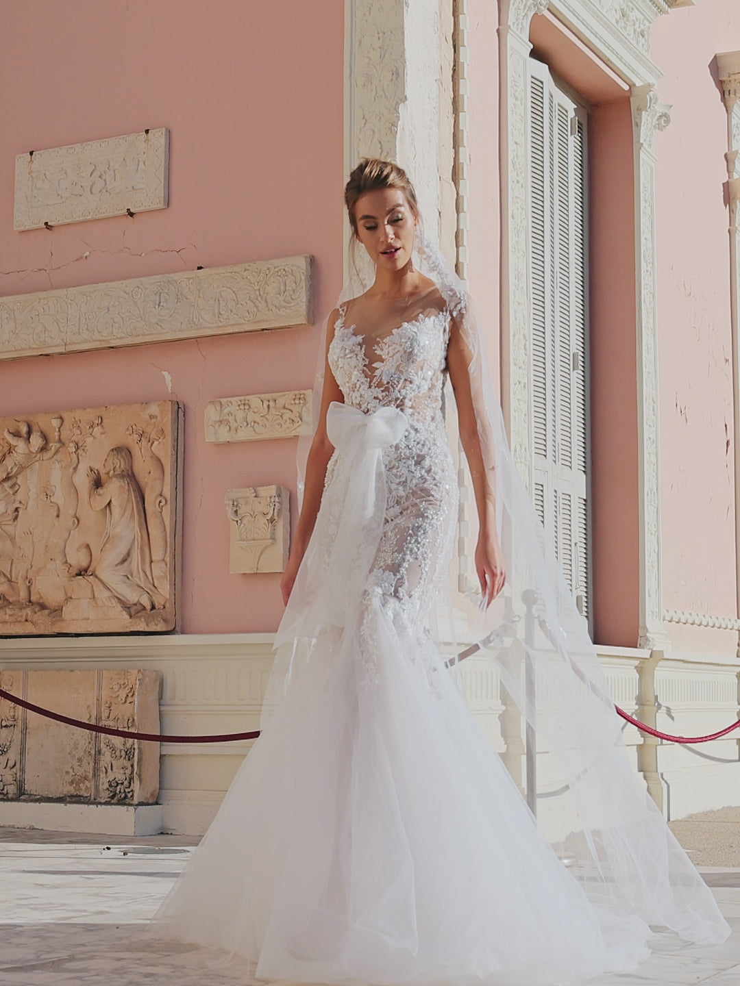 Modern mermaid wedding dress with knee-high cut, detachable waist bow, lace appliques, bead and pearl embroidery, 50 cm train, and matching veil. Made of lace and tulle for a timeless bridal look.