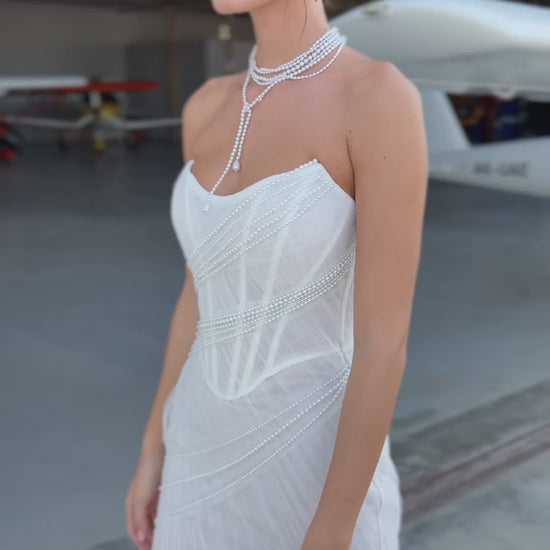 Strapless mermaid wedding dress with corrugated tulle, pearl detailing, fit and flare silhouette, and sweeping fishtail train for striking modern bridal look