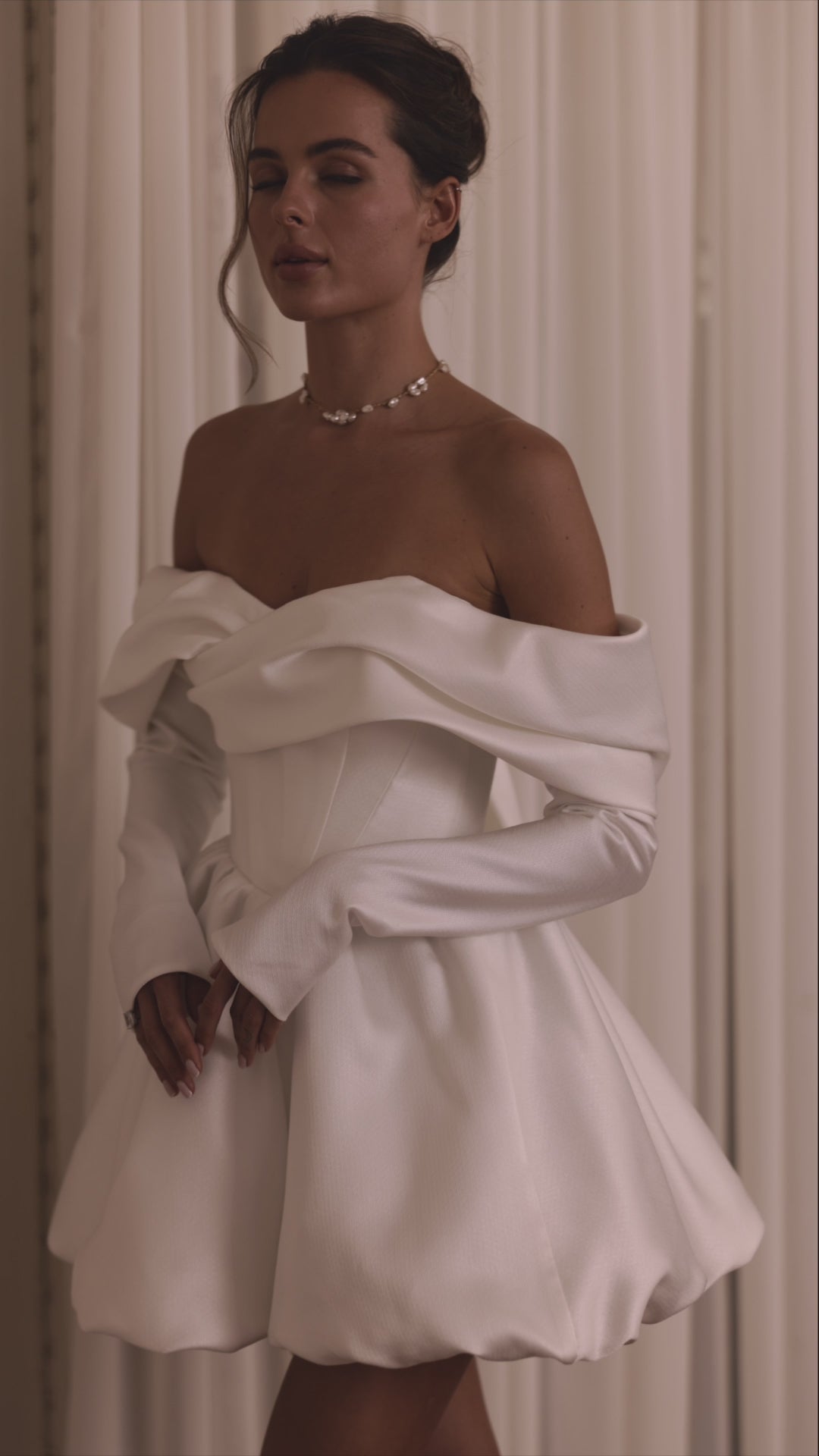 Bride wearing a two-in-one mini wedding dress with detachable mikado train and sculpted off-shoulder bodice.


