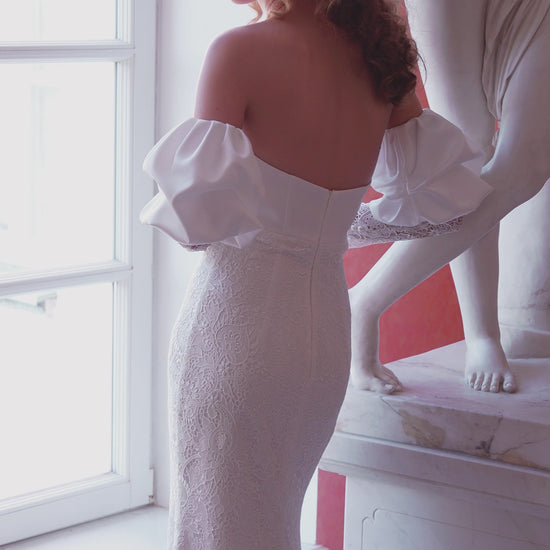 Off-shoulder lace wedding gown with puffed sleeves and fitted silhouette.