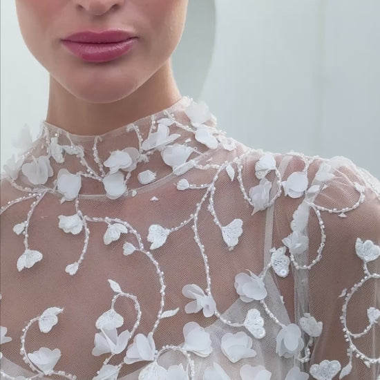 Modern 3D floral bridal mini gown with sheer long sleeves and detachable tulle overskirt.