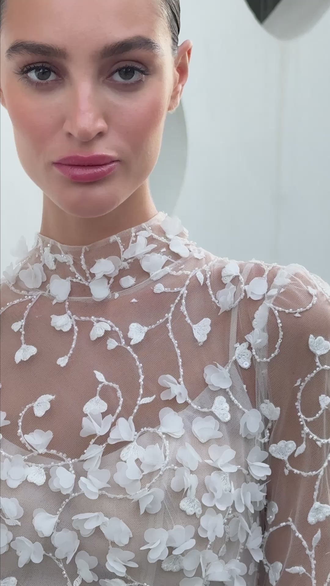 Modern 3D floral bridal mini gown with sheer long sleeves and detachable tulle overskirt.