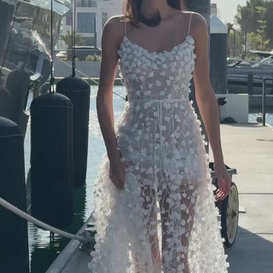 Bride wearing a sheer tulle A-line wedding gown with 3D floral appliqués from the Celeste Collection, photographed by a yacht.