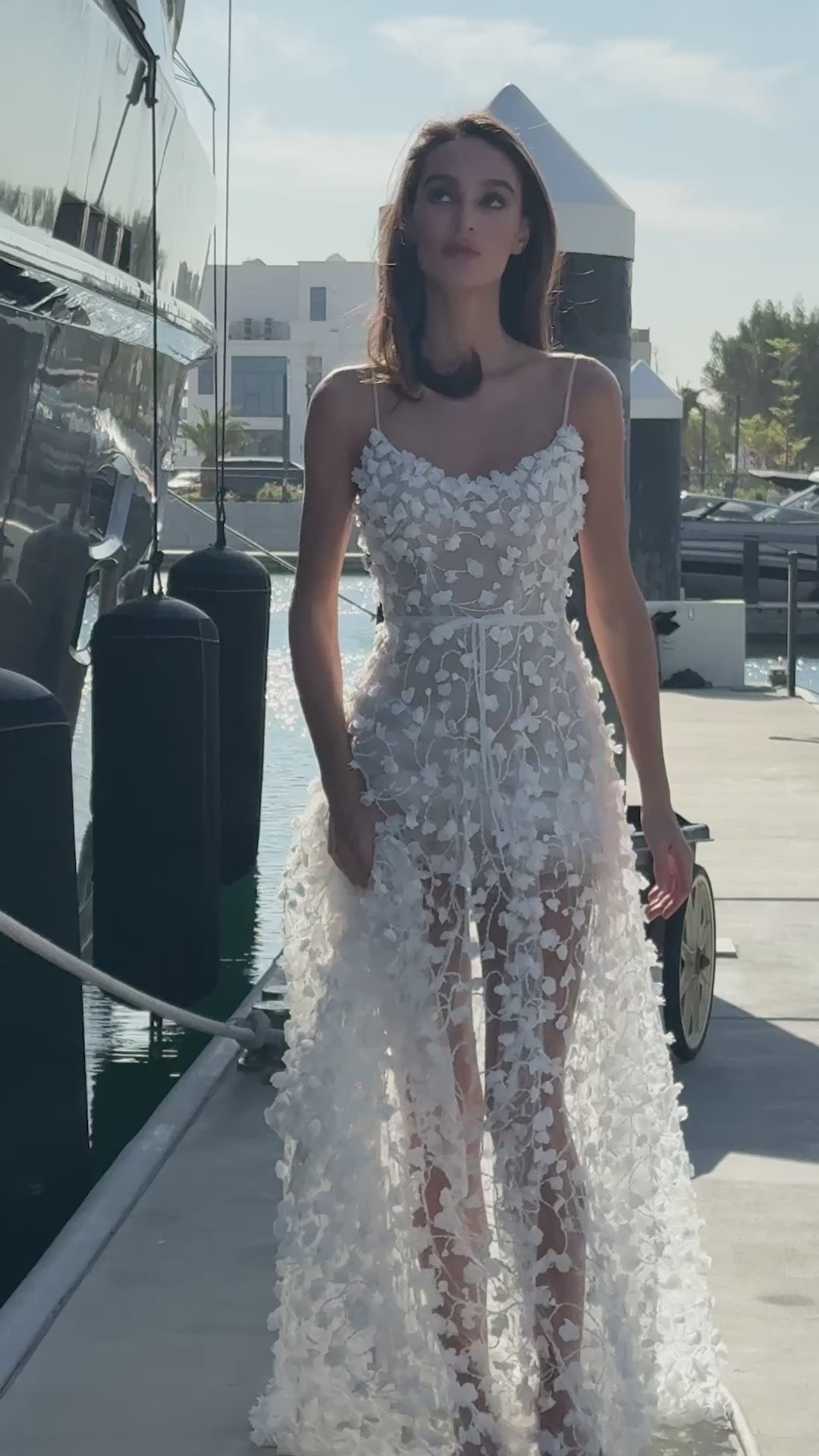 Bride wearing a sheer tulle A-line wedding gown with 3D floral appliqués from the Celeste Collection, photographed by a yacht.