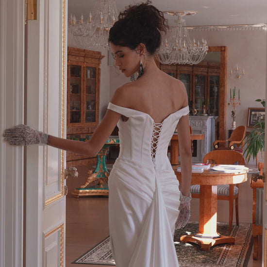 Bride in off-shoulder satin mermaid wedding gown with draped bodice, thigh-high slit, lace-up back, and sweep train.