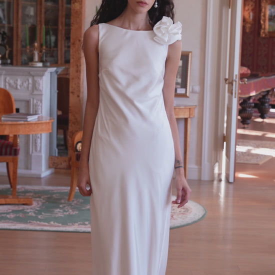 Minimalist silk wedding gown with sculpted rose shoulder and open back.