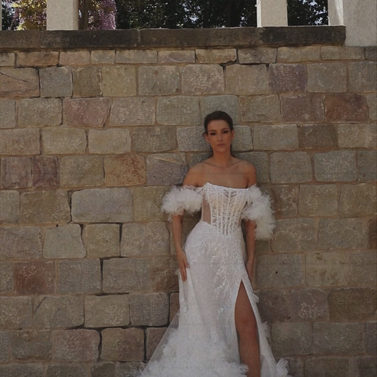 Bride in sleeveless tulle A-line wedding gown with pearl-adorned lace, 3D floral appliqués, boat neckline, slit skirt, drop waist, and straight open back.
