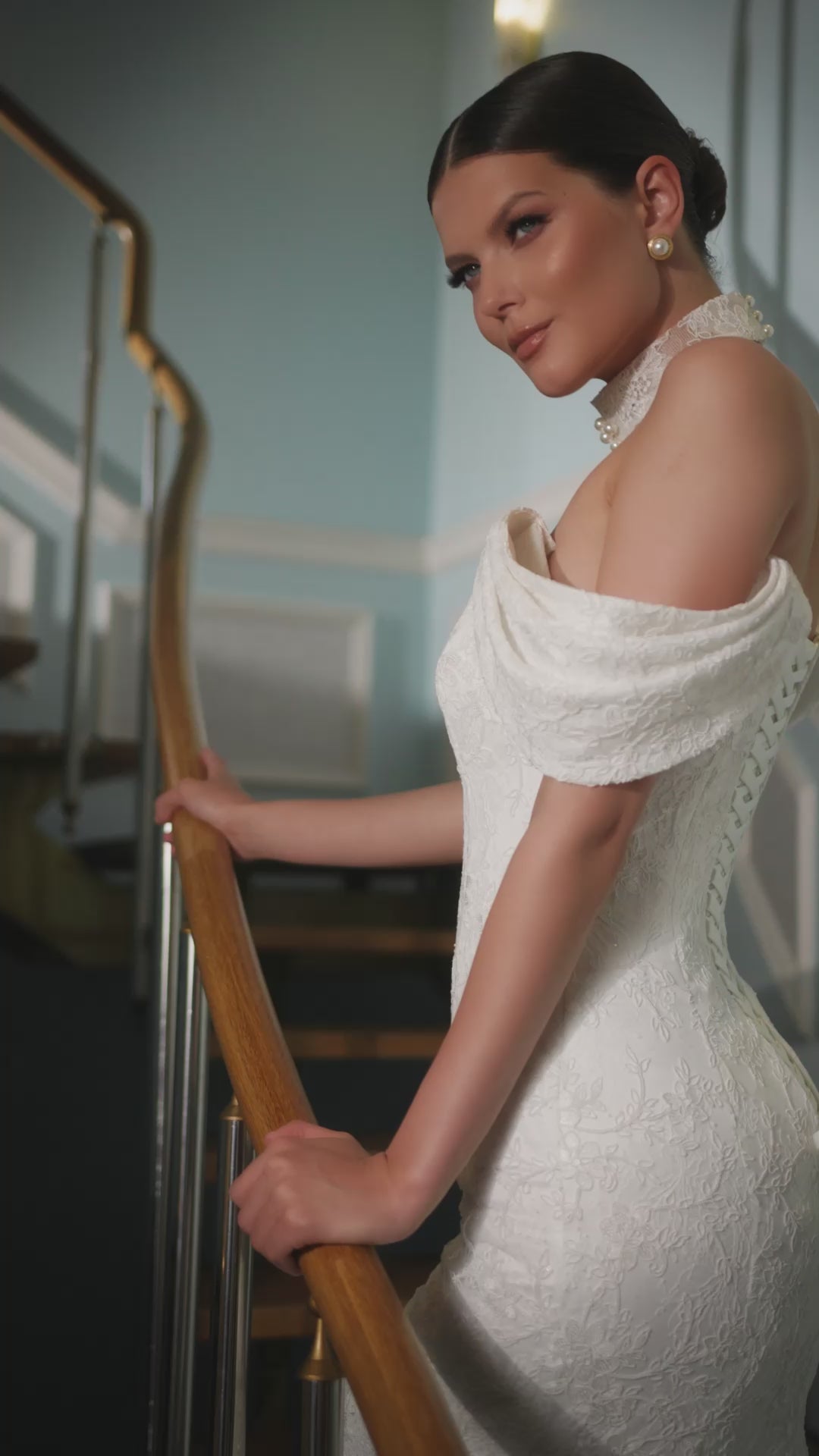 Full-length lace mermaid wedding dress with fit and flare silhouette, draped off-shoulder sleeves, V-neckline, removable lace and pearl choker, lace-up back closure, and elegant fishtail train for modern bridal look