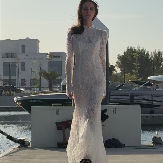 Celeste beaded lace long-sleeve sheath wedding dress with high neck and detachable tulle overskirt, open-back detail.