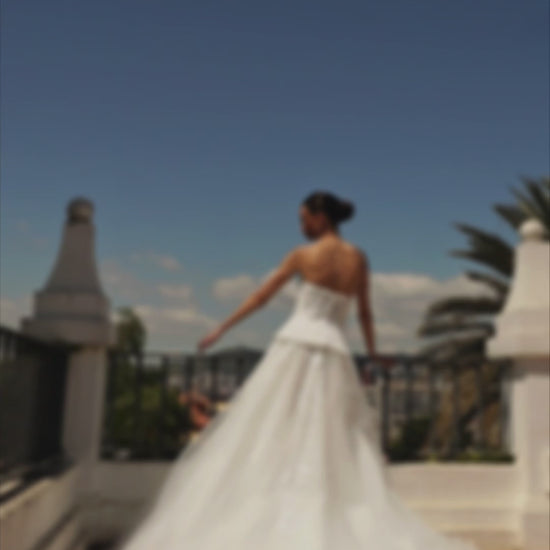 Bride in strapless sweetheart sleeveless A-line wedding gown with sequin lace corset, flowing tulle skirt, and chapel train.