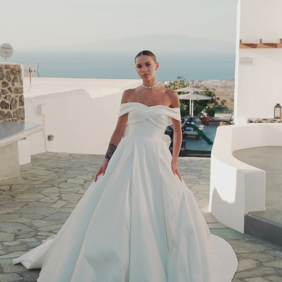 A-line wedding dress with off-the-shoulder neckline and bow.