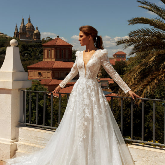 Bride in long sleeve lace A-line bridal gown with puffy shoulders, illusion deep-V back, button closure, and chapel train.