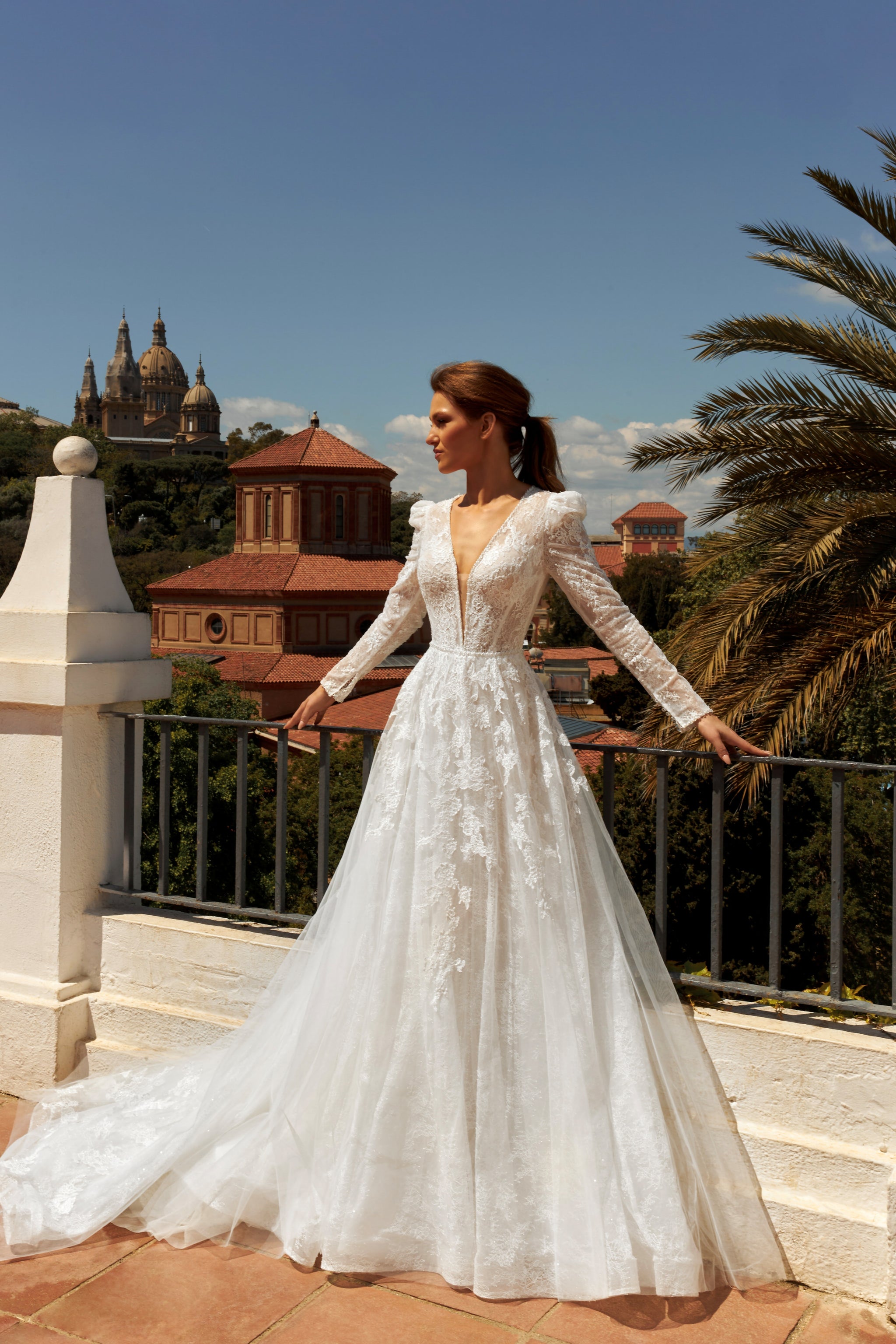 Bride in long sleeve lace A-line bridal gown with puffy shoulders, illusion deep-V back, button closure, and chapel train.