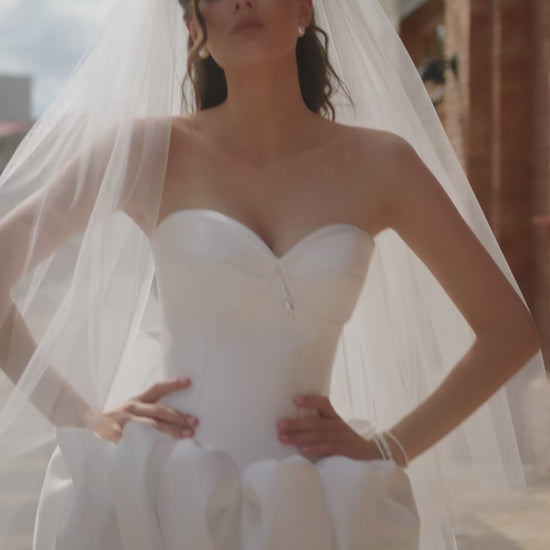 Bride in strapless Mikado mini wedding dress with corset-style bodice and bubble-hem skirt, ideal for reception or city celebration.