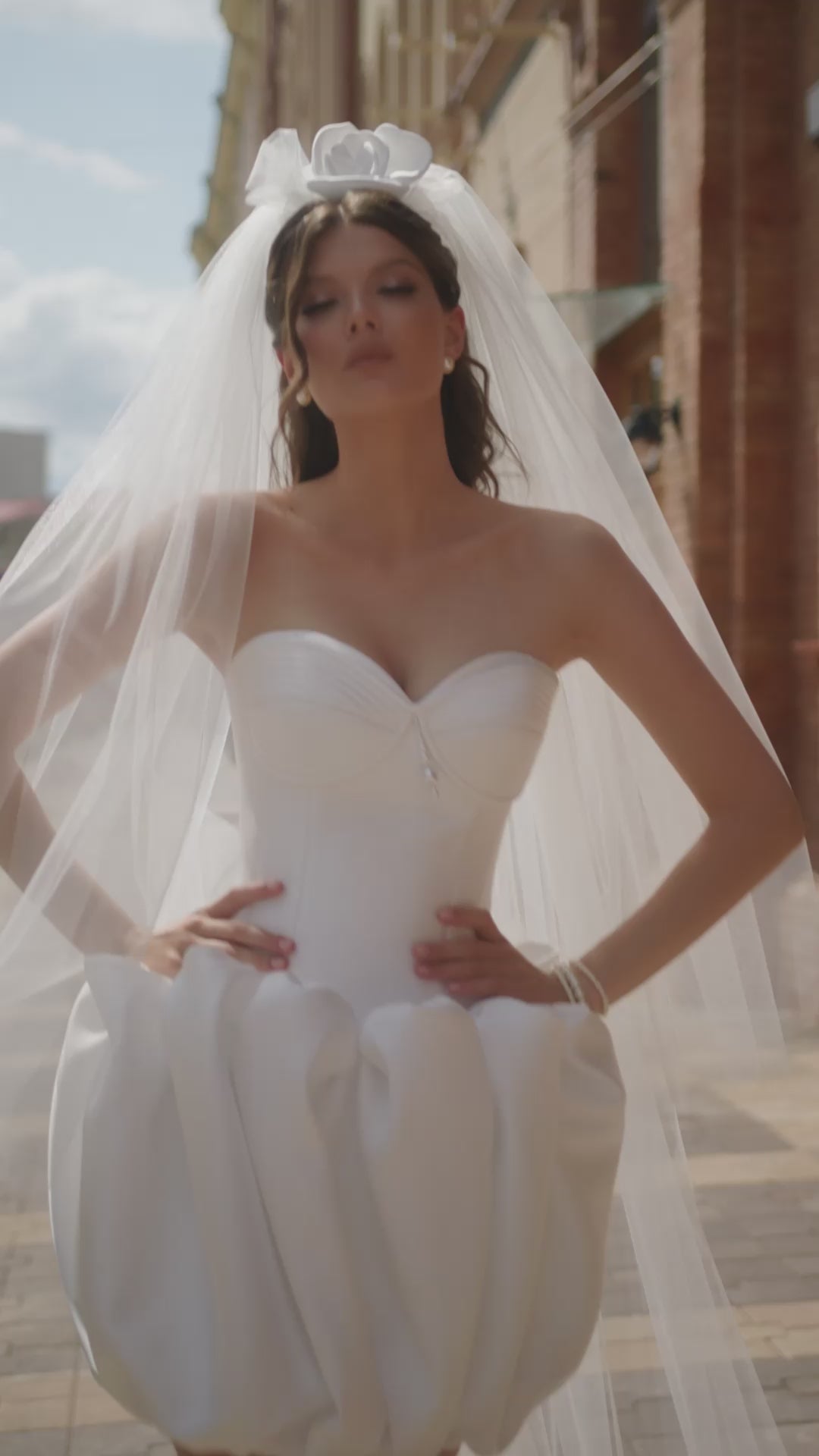 Bride in strapless Mikado mini wedding dress with corset-style bodice and bubble-hem skirt, ideal for reception or city celebration.