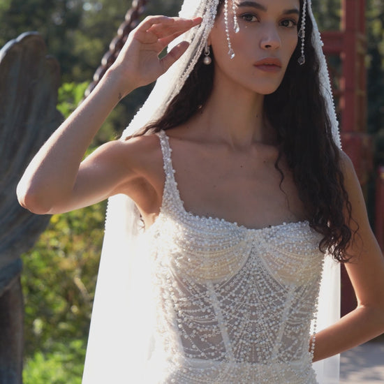 Beaded mermaid wedding gown with geometric pearl embroidery, sheer corset bodice, and elegant train.