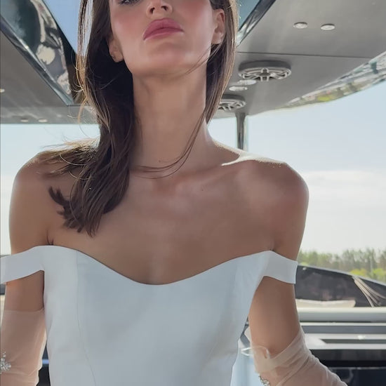 Bride wearing an off-shoulder corset wedding gown with train and optional Mikado overskirt from the Celeste Collection, photographed on a yacht.