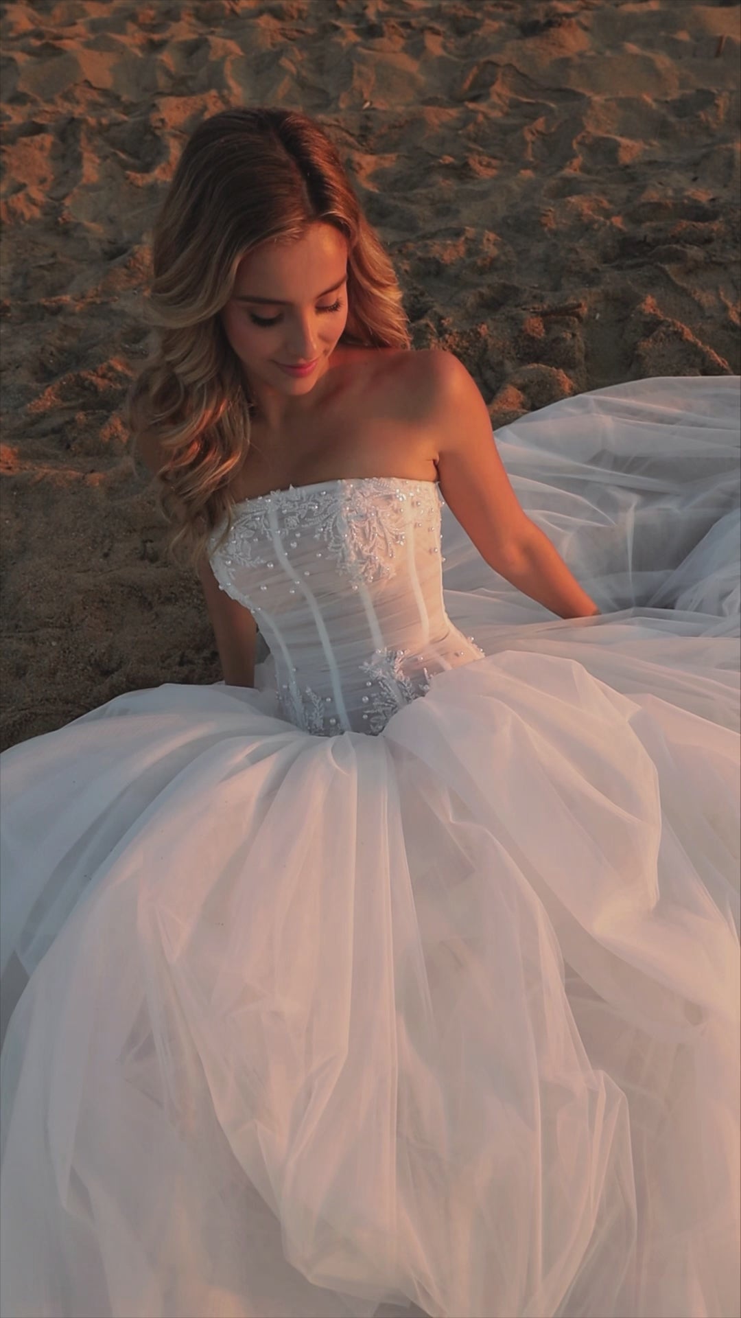 Bride in strapless soft tulle wedding gown with pearl and lace embellished prolonged bodice, zip closure, and chapel train.