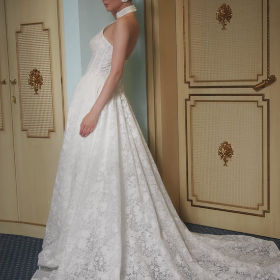 Lace A-line halter wedding dress with long removable sleeves adorned with 3D flowers, drop-down waist waspie corset, open lace-up back, and flowing chapel train for romantic bridal look